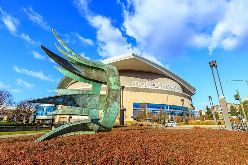Holladay Park Plaza Moda Center outdoor view. A green sculpture that resembles a sideways crown is in the foreground.