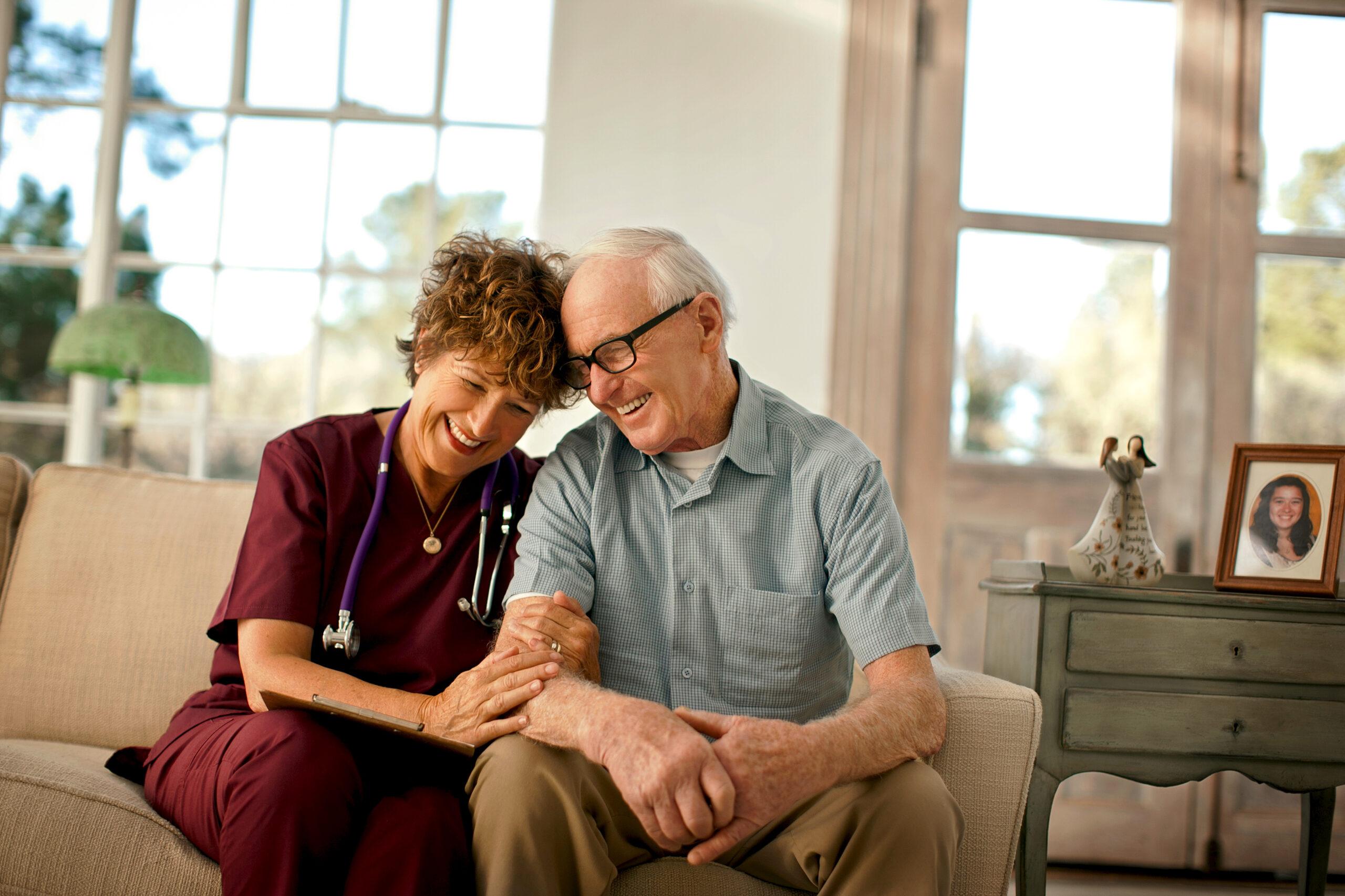 An at-home care nurse smiles and comforts a patient.